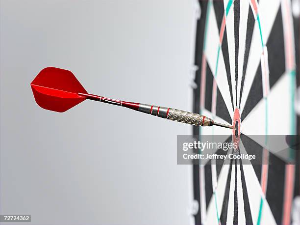 dart in bullseye of dart board, side view, close-up - exactitud fotografías e imágenes de stock