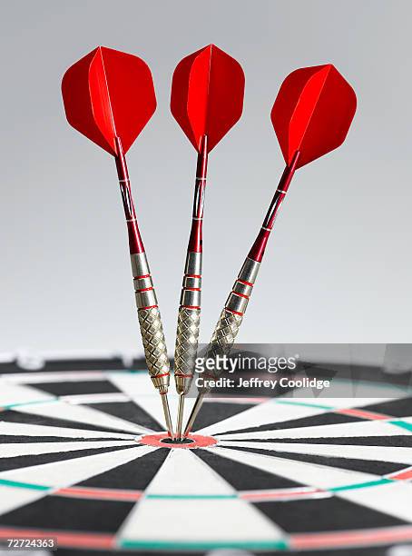 three darts in bulls eye of dart board, side view, close-up - dart board stock-fotos und bilder