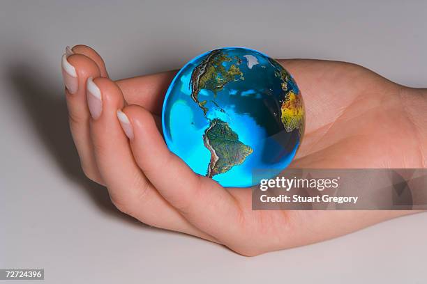 human hand holding glass globe, elevated view, close-up - world at your fingertips stockfoto's en -beelden