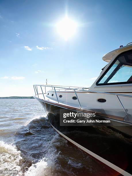 power boat moving through water with sun shining on lake, side view - power boat stock pictures, royalty-free photos & images