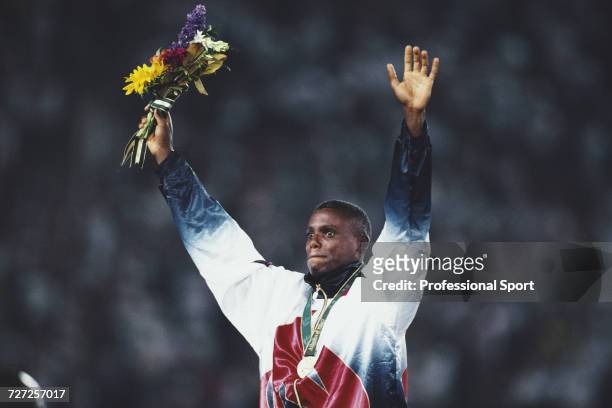 American athlete Carl Lewis raises his arms in the air in celebration on the medal podium after finishing in first place to win the gold medal in the...