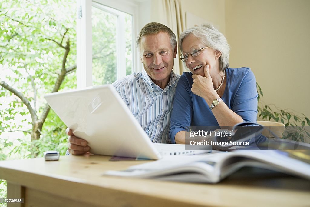 Couple âgé avec ordinateur portable et de brochures