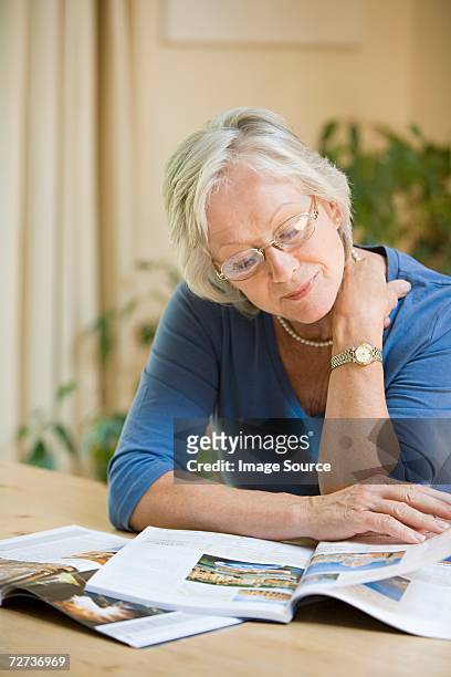 woman looking at holiday brochures - magazines on table stock pictures, royalty-free photos & images