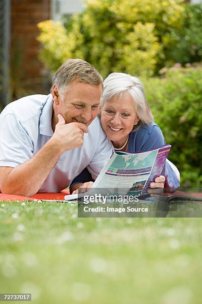 couple looking at holiday brochure - magazine retreat day 2 stock pictures, royalty-free photos & images