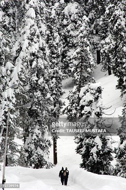 An Indian Kashmiri men walk along a snow covered road at the ski-resort of Gulmarg, 52kms west of Kashmir's summer capital Srinagar, 06 December...