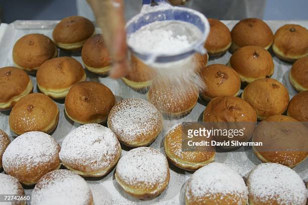 Fresh oil-fried doughnuts, called sufganiyot in Hebrew, are dusted with icing sugar before going on display at the Roladin bakery December 6, 2006 in...
