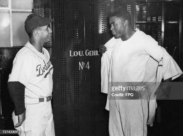 Brooklyn Dodgers catcher Roy Campenella, left, and second baseman Jackie Robinson, get dressed before a pre-season exhibition game with the Yankees...