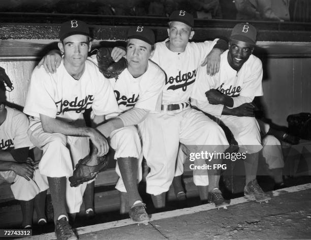 Newest Brooklyn Dodgers recruit Jackie Robinson on the end of the bench with his team mates at Ebbet's Field, 1947. Robinson was the first African...