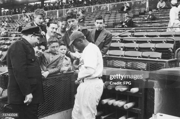 Baseball player Jackie Robinson signs autographs for Brooklyn Dodger's fans, late 1940s.