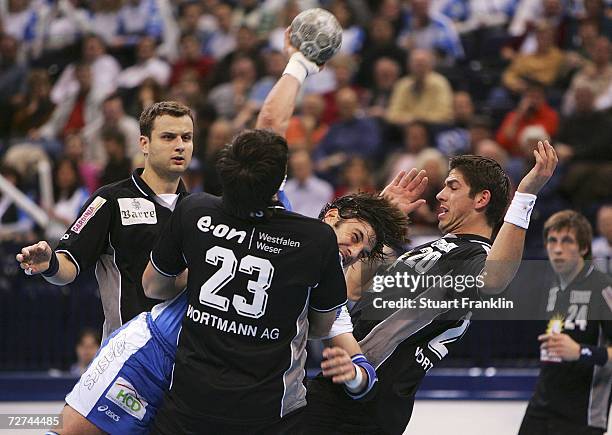 Bertrand Gille of Hamburg throws a goal as he is challenged by Damjan Blecic and Rolf Herrmann of Lubeck during the Bundesliga game between HSV...