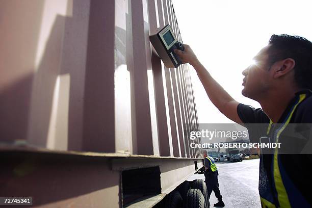 An agent from the US Customs and Border Protection section of the US Homeland Security Department places a Geiger counter on the side of a container...