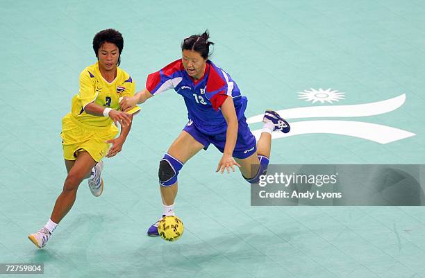 Park Chung Hee of South Korea and Jitthita Sipak of Thailand reach for a loose ball during their match in the Handball competition during the 2006...