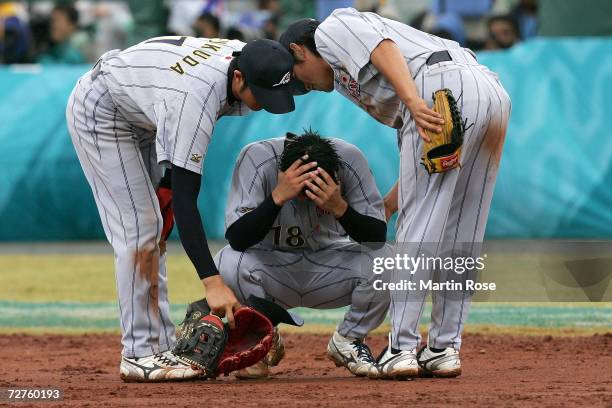 Pitcher Kentaro Takasaki is consoled by teammates after Lin Chih Sheng of Chinese Taipei hit a game winning two-run single in the ninth inning...