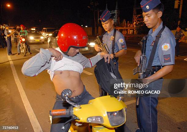 Policemen check a motorcycle driver for weapons at a checkpoint in Cebu city 07 December 2006 as part of tight security for the coming annual...