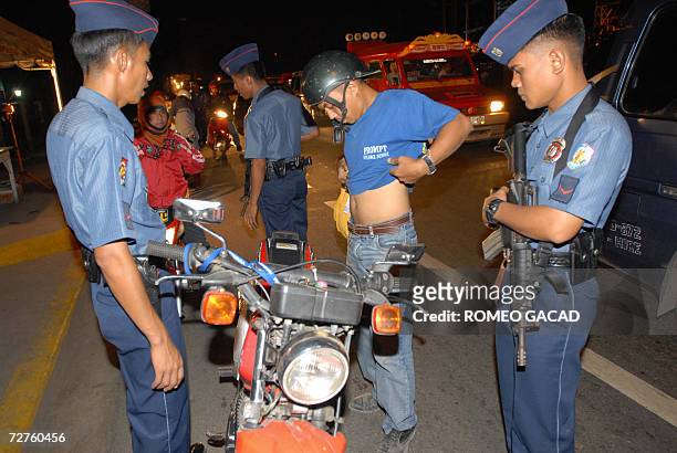 Policemen check a motorcycle driver for weapons at a checkpoint in Cebu city 07 December 2006 as part of tight security for the coming annual...