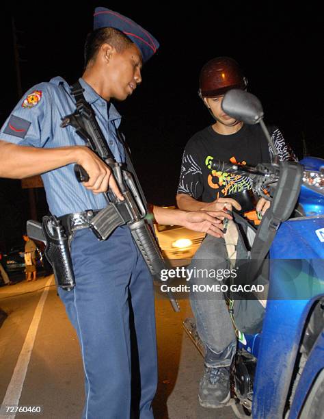 Policemen check a motorcycle driver for weapons at a checkpoint in Cebu city 07 December 2006 as part of tight security for the coming annual...