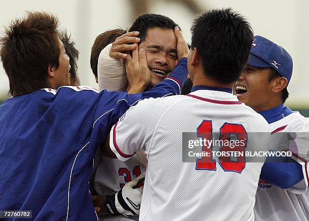 Taiwan's last batsman Lin Chih Sheng is embraced by his teammates after winning over Japan at the Baseball Single Round Robin Final during the 15th...