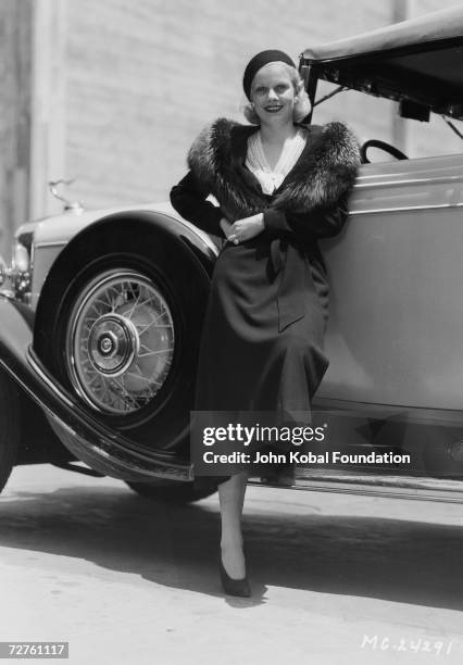 American actress Jean Harlow leans on a car, 15th June 1932.