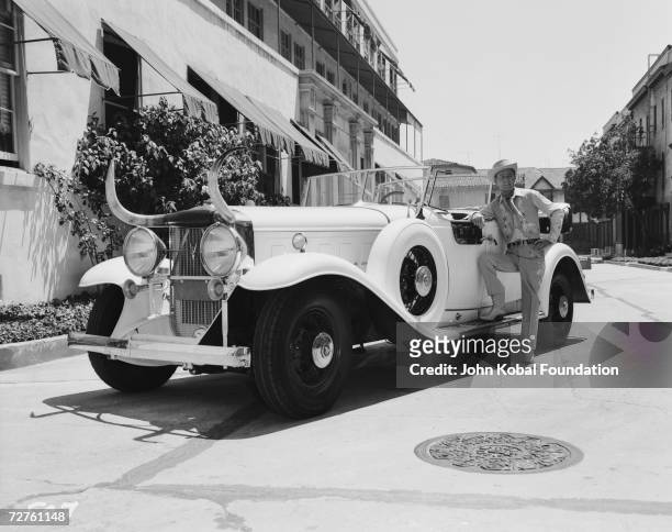 Western star Alan Ladd poses next to a car decorated with a large pair of horns, circa 1935.
