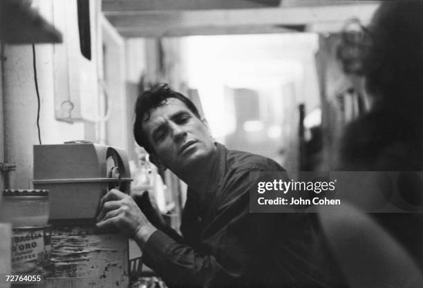 American Beat writer Jack Kerouac leans closer to a radio to hear himself on a broadcast, 1959.