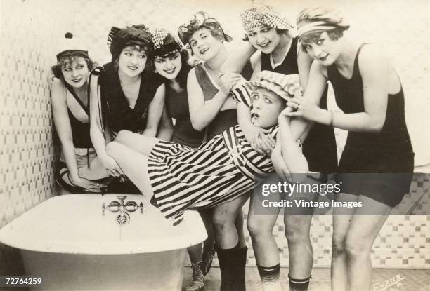 Postcard image by Evans shows the young slapstick comedy actresses known as the 'Mack Sennett Bathing Beauties' as they gather around a bathtub to...