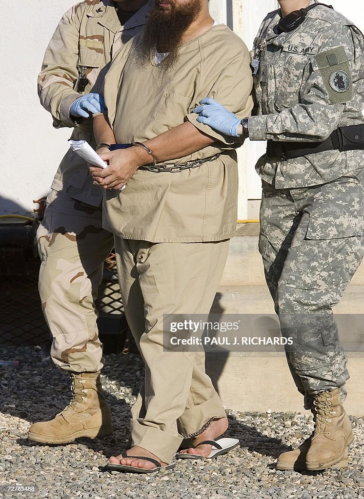 A detainee is escorted by military guard