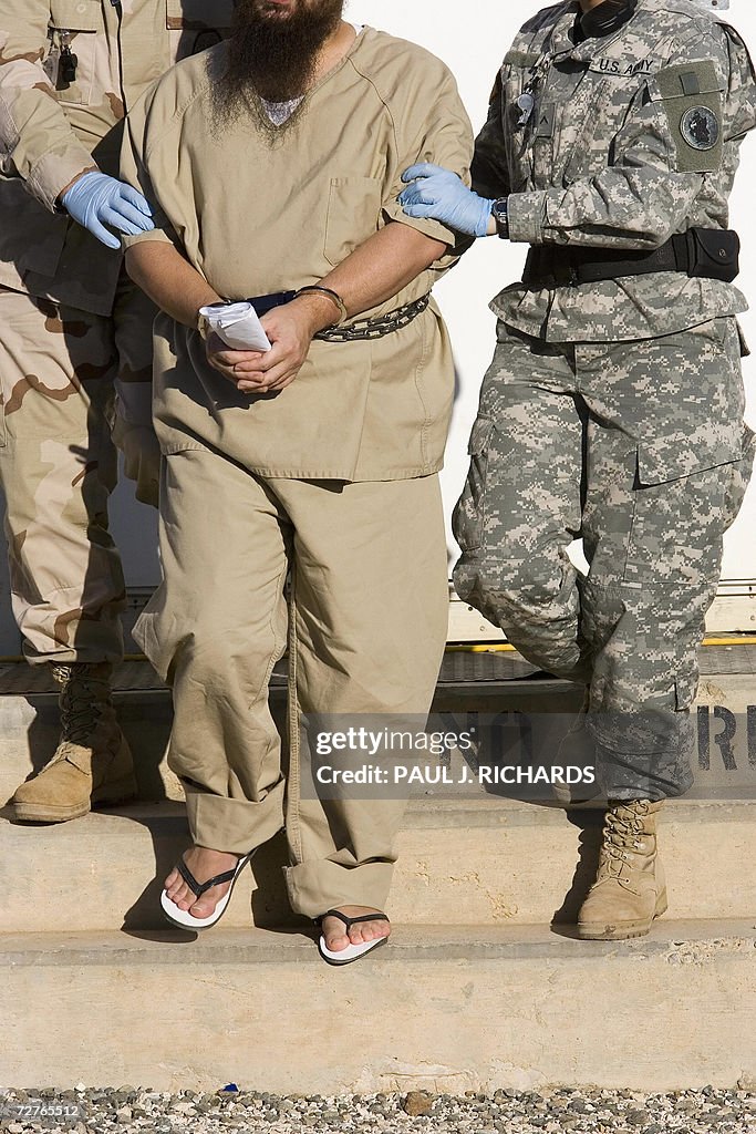 A detainee is escorted by military guard