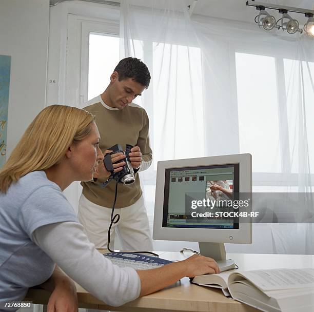 blond woman and brunette man sitting in front of a computer - filming - studio - brunette sitting at desk stock-fotos und bilder