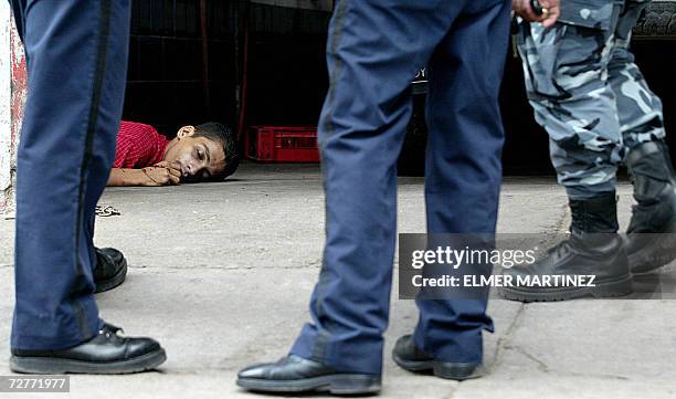 Tegucigalpa, HONDURAS: Agentes de la Policia Nacional de Honduras observan uno de los cuatro supuestos asaltantes que murieron durante un tiroteo con...