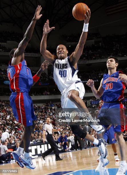 Devean George of the Dallas Mavericks shoots the ball between Antonio McDyess and Carlos Arroyo of the Detroit Pistons during an NBA game on December...