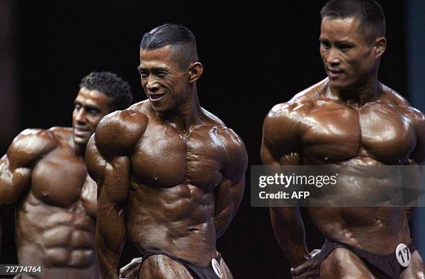 Chinese body builder Qian Ji Cheng , winner of the gold medal in the 60 kg catergory, shows his muscles along with South Korean Cho Wang Bung and...