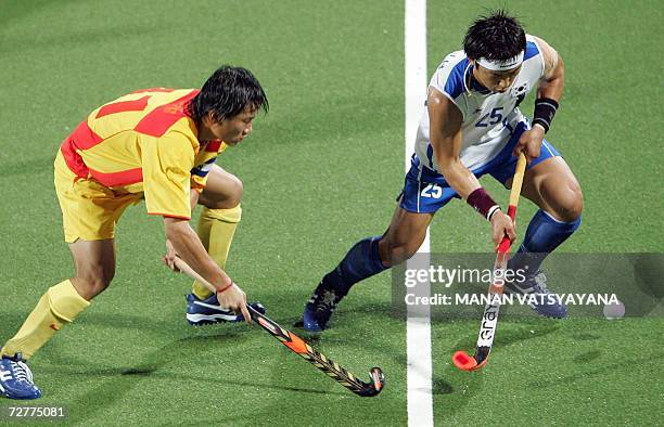 South Korean Jang Jong Hyun is challenged by Chinese captain Song Yi during the Men's Hockey Pool B match at the 15th Asian Games in Doha 08 December...