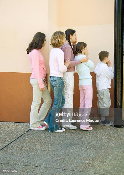 group of kids standing in line, come covering mouths - espiar una conversación fotografías e imágenes de stock