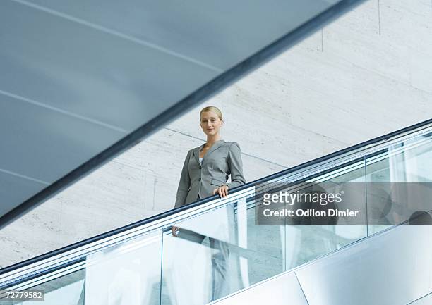 businesswoman going down escalator - rigor fotografías e imágenes de stock