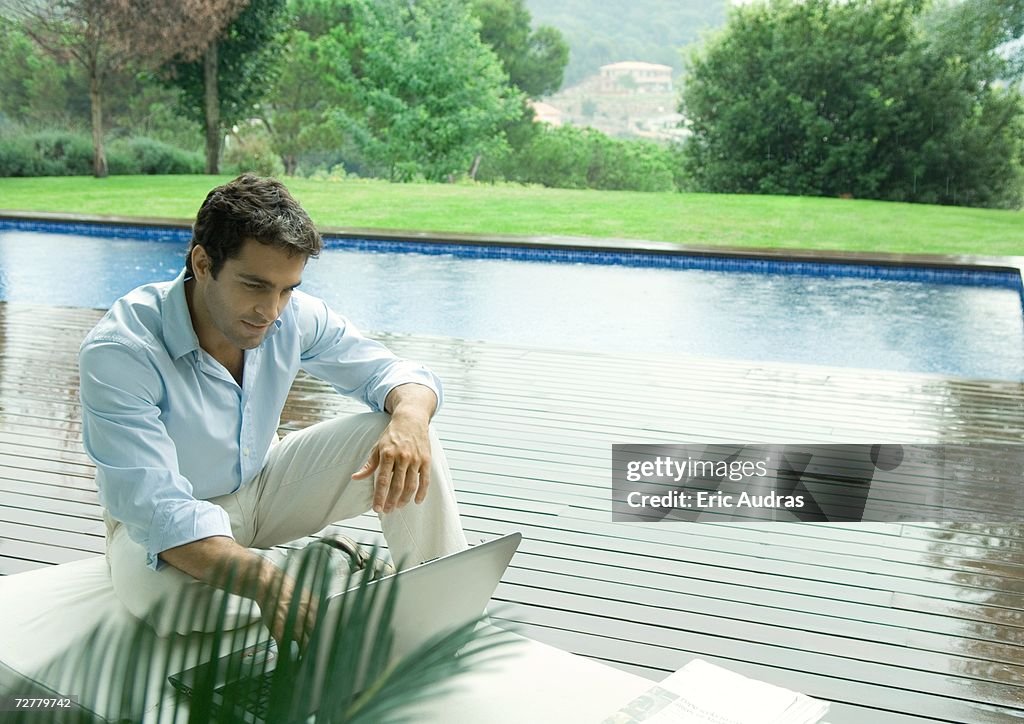 Casually dressed young executive working near edge of pool
