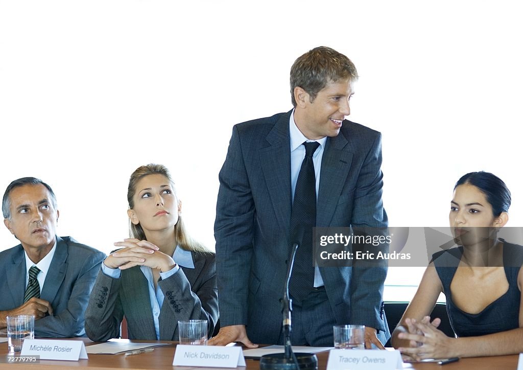 Executives sitting at conference table, one man standing