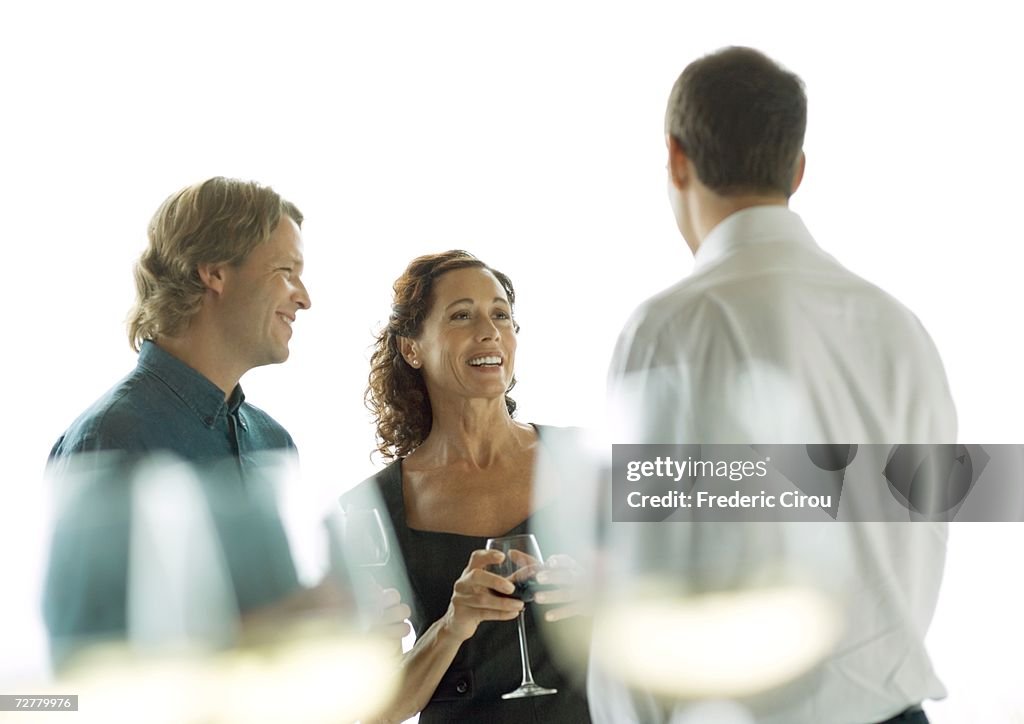 Three people chatting and drinking wine