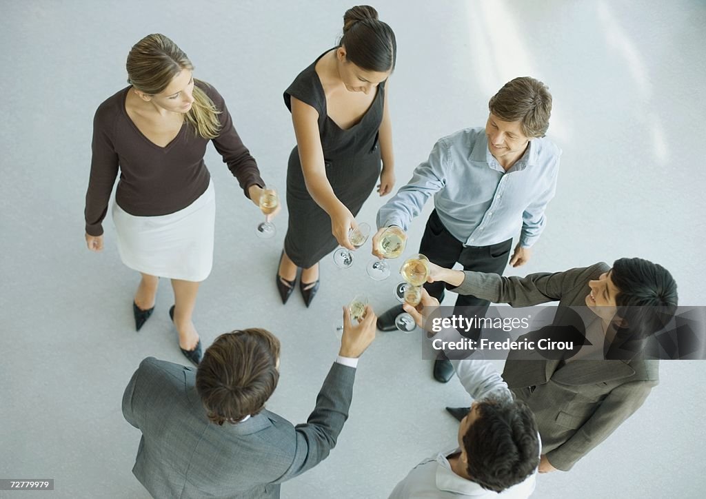 Young executives raising glasses for toast, high angle view