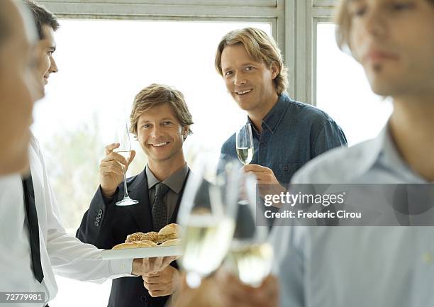 two male executives raising glasses of champagne during office party - cocktail corporate stockfoto's en -beelden