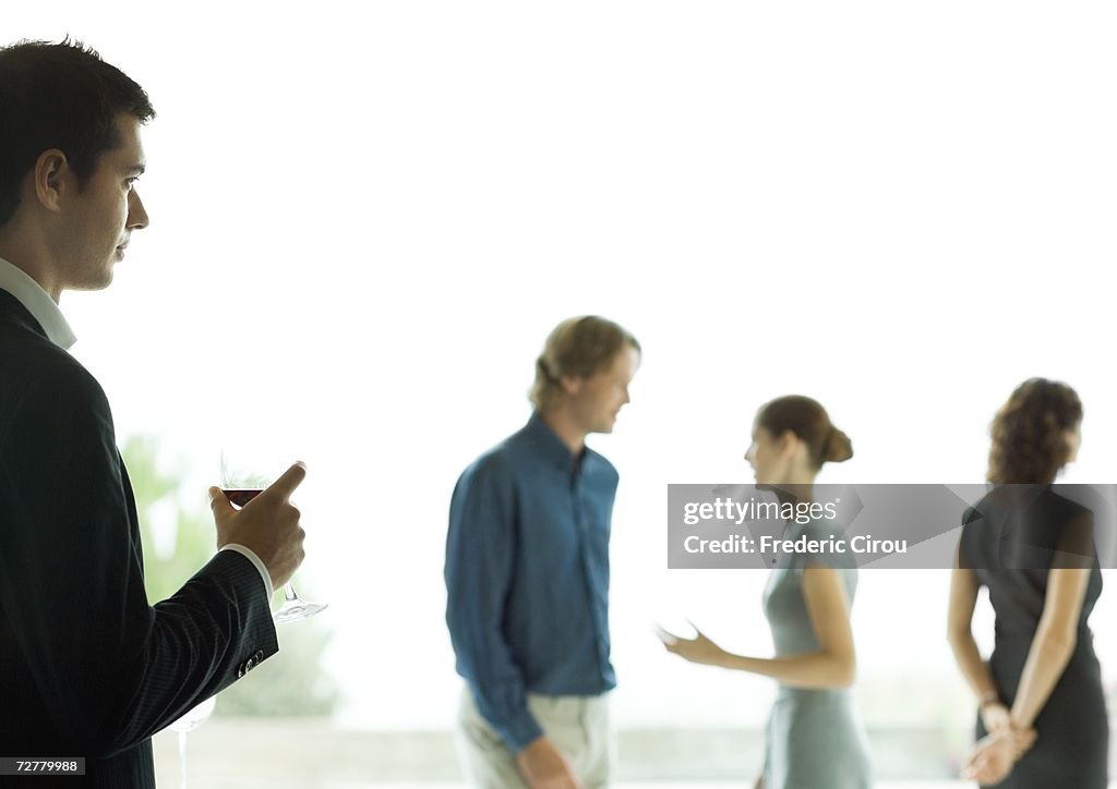 Man watching man and woman talk during cocktail party