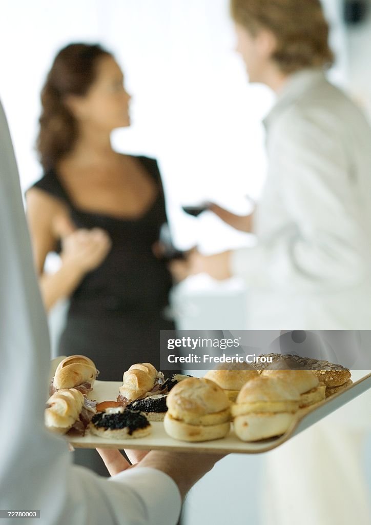 Server holding tray of appetizers during cocktail party