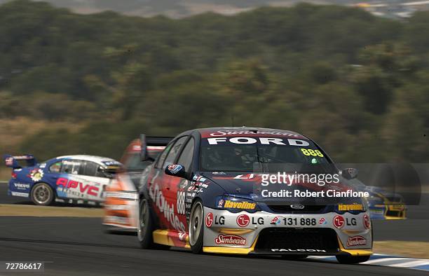 Craig Lowndes of Triple Eight Race Engineering is chased by Rick Kelly of the Toll HSV Dealer Team during race two of round 13 of the V8 Supercars at...