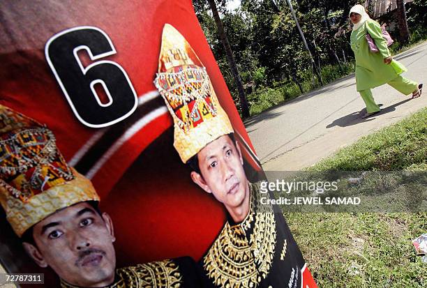 Woman walks past an election poster displayed on a electric pole in Aceh Besar, 10 December 2006, a day before the provincial election. The...