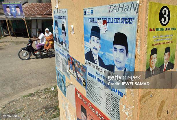 Man with his family ride past electoral posters in Aceh Besar, 10 December 2006, a day before the provincial election. The relatively trouble-free...
