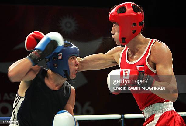 Kim Song Guk of North Korea punches Bahodirjon Sultanov of Uzbekistan in the men's boxing feather 57kg quarter-final during the 15th Asian Games in...