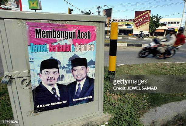 Banda Aceh, INDONESIA: A motorist drives past an election poster along a street in Banda Aceh, 10 December 2006, a day before the provincial...