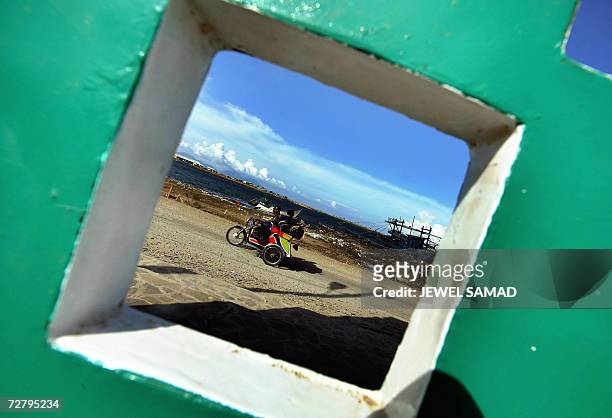 Banda Aceh, INDONESIA: A man drives his "Bicha" a three-wheeler converted from motorbike, along a street in Banda Aceh, 10 December 2006, a day...