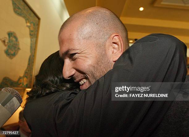 French football star Zinedine Zidane smiles as a fan hugs him upon his arrival 11 December 2006 at Houari Boumediene international airport in Algiers...