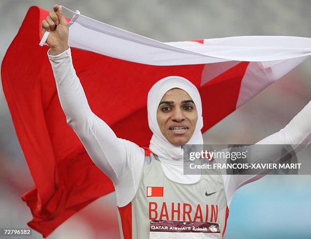 Bahrain's Ruqaya Al Ghasara holds her country's flag as she celebrates winning the women's 200m final on the fourth day of the athletics competition...