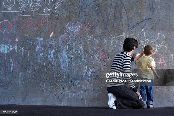 father and son (3-4 years) writing in chalk on wall - chalk wall stock pictures, royalty-free photos & images